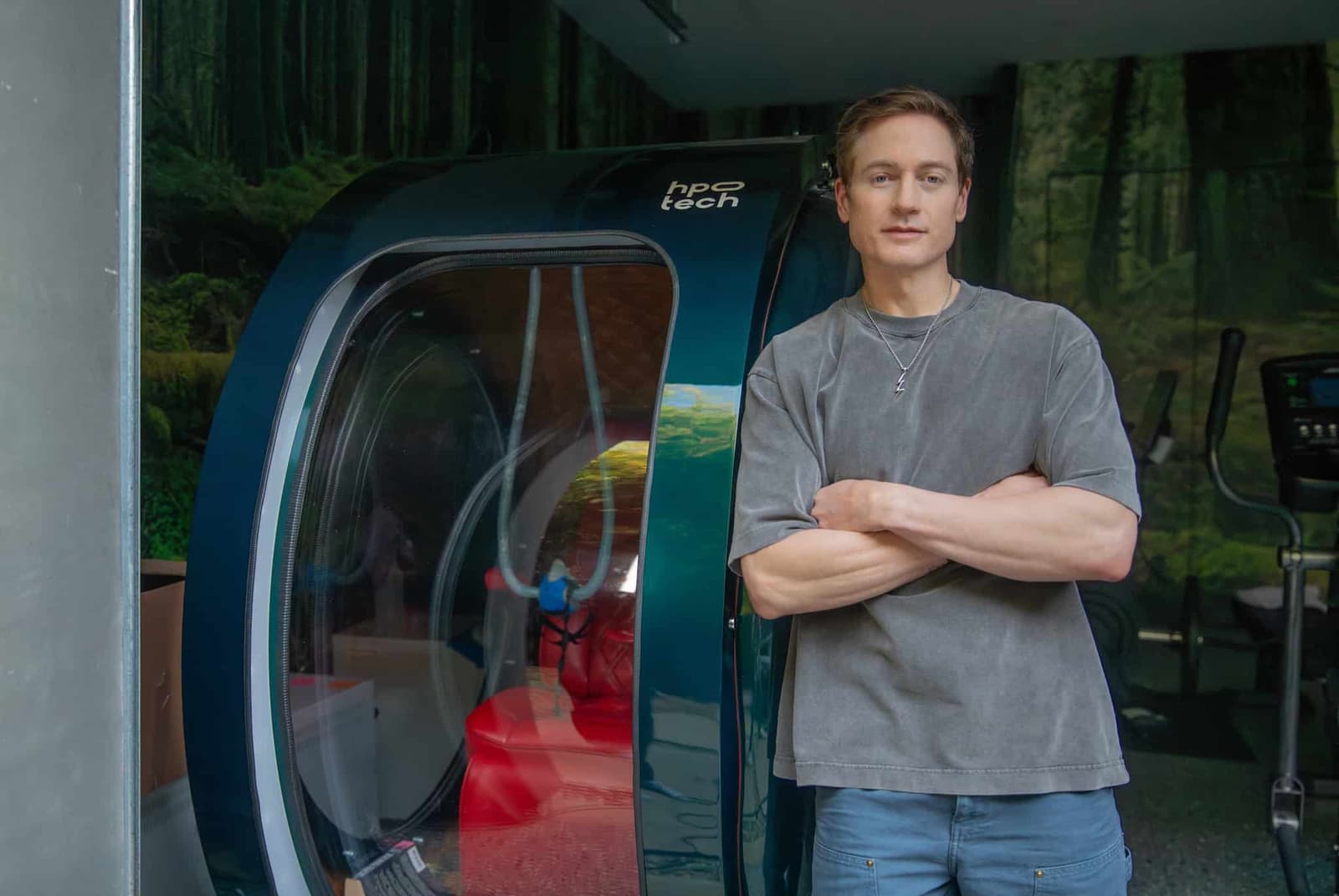 Bryan Johnson is standing next to a hyperbaric chamber.