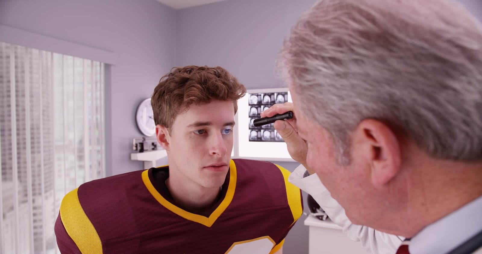 A doctor is inspecting a young patient's right eye with a flashlight.