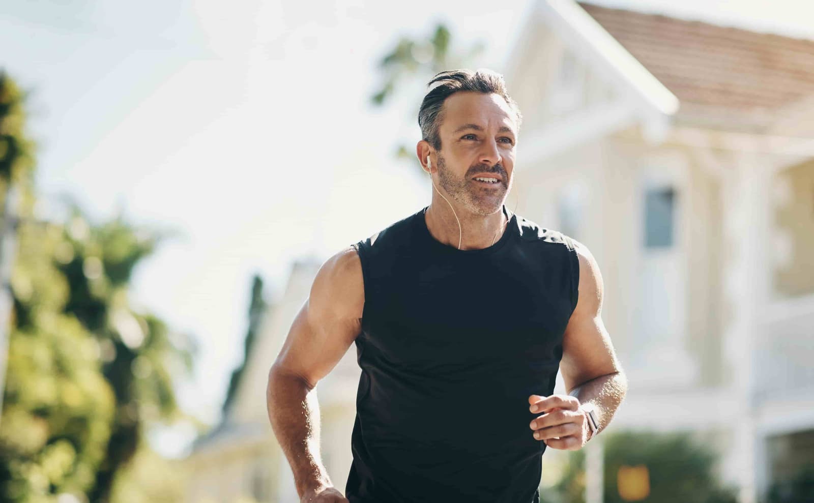 A middle-aged man is jogging through a neighborhood.