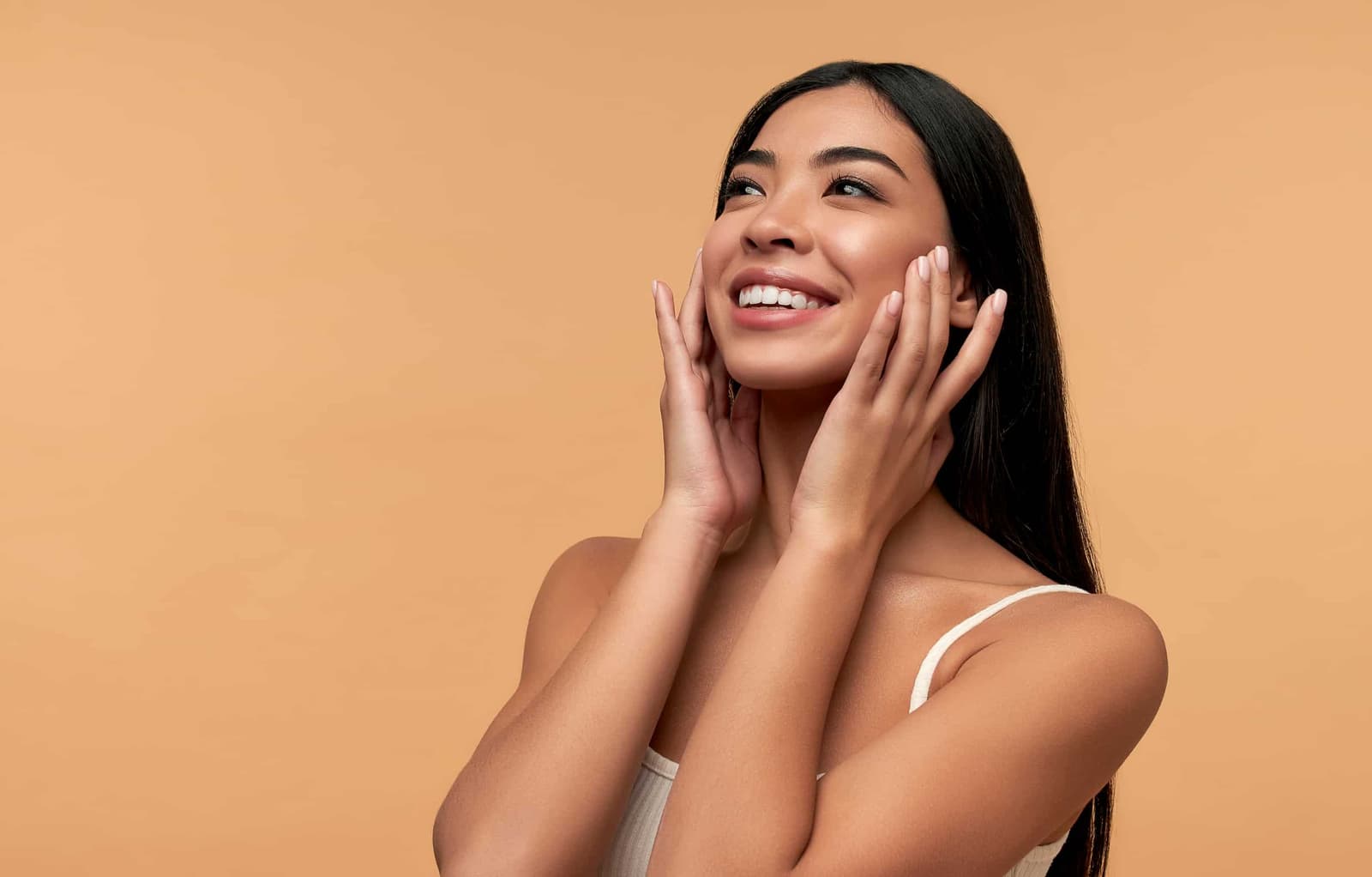A woman is smiling while touching her face.