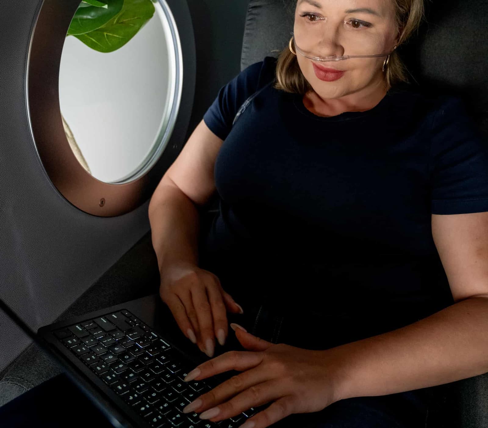 A woman is seen working on a laptop inside the OxyRenew hyperbaric chamber.